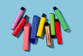 Set of colorful disposable electronic cigarettes on a blue background. The concept of modern...