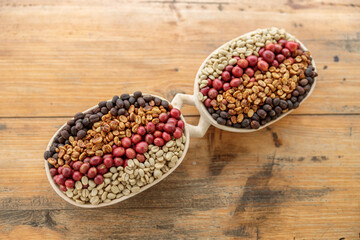 Top view of coffee beans of different processing processes in bowl on wooden table