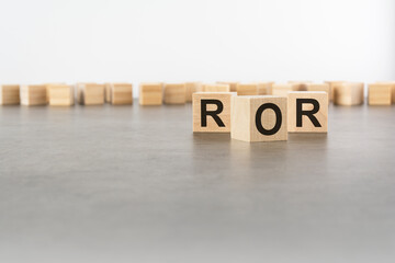 three wooden blocks with letters ROR with focus to the single cube in the foreground in a conceptual image on grey background