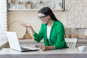 Woman disappointed sad and angry at home in the kitchen trying to make an online purchase in an...