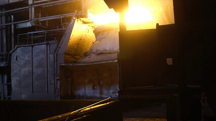 Interior view of steel mill with huge ladle of burning metal alloy. Footage. View of open-hearth...