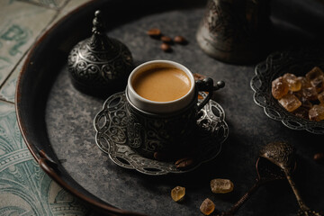 Coffee in metal Turkish traditional cup and coffee beans on tile background