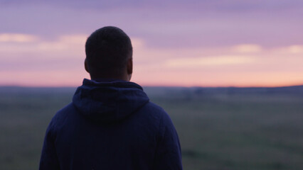 Young man is looking at the sunset thinking. Young man looks at the sunset, being alone, the...