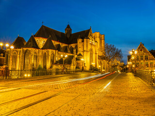 Cobble Stones road on top of Sint-Michielsbrug Arched stone bridge and Saint Michael's Church at night in Ghent, Belgium