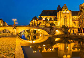 Historic medieval building and Arched stone bridge at night on Leie river in Ghent, Belgium
