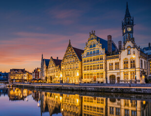 Fototapeta premium Historic medieval building illuminated after sunset on Leie river in Ghent, Belgium