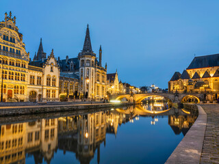 Historic medieval building illuminated at dusk on Leie river in Ghent, Belgium