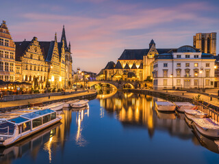 Naklejka na ściany i meble Historic medieval building illuminated at night on Leie river in Ghent, Belgium