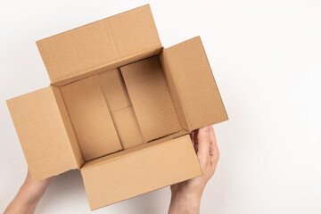 Female hands with empty open brown cardboard box on white background. Top view