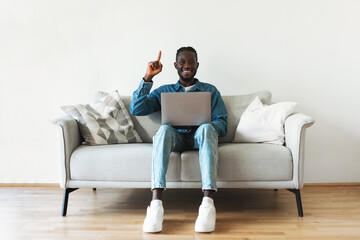 Fototapeta na wymiar Black Millennial Man Using Laptop Having Great Idea Sitting Indoors
