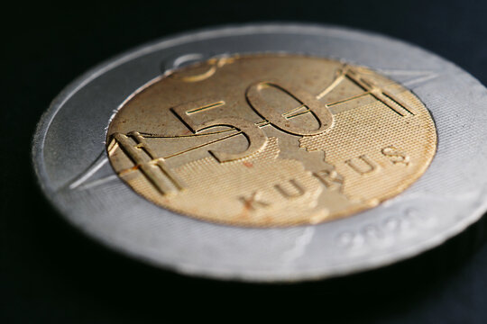 Translation: 50 kurus. Turkish coin of 50 kuruş lies on a dark surface close-up. National currency of Turkey. Illustration for news about economy or finance. Bosphorus Bridge. Macro