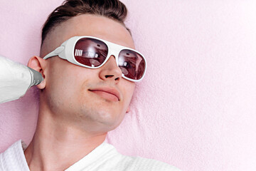 Portrait of a young handsome man on a pink background with glasses. A man in a beauty salon...