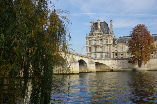 view of the louvre museum from the seine river by the old stone bridge in paris france