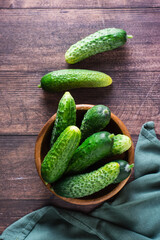 Fresh whole cucumbers in a bowl and on a wooden table. Diet organic food. Top and vertical view