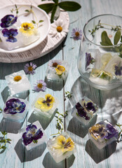 Summer flowers frozen in the ice on the table, plate and in the glass 