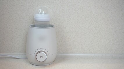 A woman puts a bottle of food into a bottle warmer. Apparatus for rapid heating and stirring of...