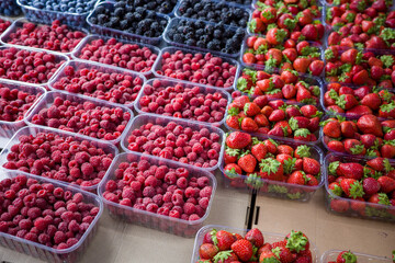 Fresh ripe berries in plastic containers on the counter