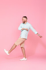 Fototapeta na wymiar cheerful young happy man dance on pink background.