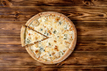 Pizza with four cheeses, mozzarella, blue cheese, Parmesan cheese. Italian cuisine. On a wooden background. View from above.
