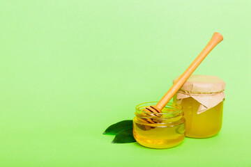 Honey in jar with leaves and honey dipper on colored background top view with copy text