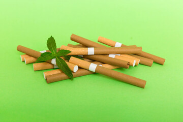Menthol cigarettes and fresh mint leaves on colored background, Many cigarettes stacked together...