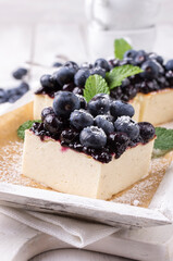 Traditional German cheesecake with blueberry fruits served as close-up in a cake dish on a wooden tray