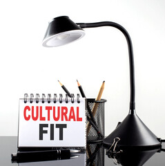 CULTURAL FIT text on notebook with pen and table lamp on the black background