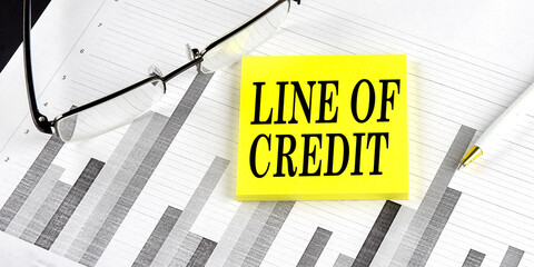 Word LINE OF CREDIT on yellow sticky on the chart background
