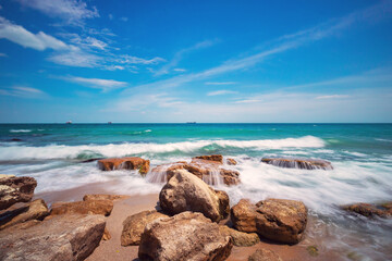 Wild exotic beach with rocks in sea water. Rocky island coastline