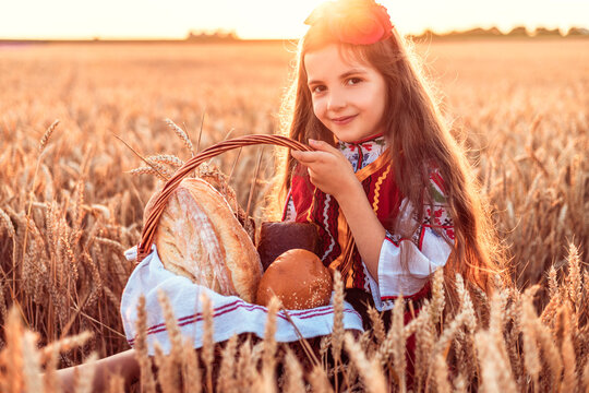 Bulgarian woman  or young girl in traditional folklore dress holds in hands golden wheat and freshly baked homemade bread in a bag