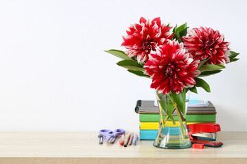 A bouquet of red dahlias and school supplies.