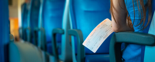 A woman with a ticket is sitting in a clean and empty train - obrazy, fototapety, plakaty