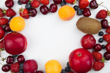 Different fruits and berries lie on a white background on the sides of the photo, forming a frame with an empty space in the middle for the text. High quality photo