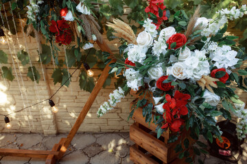 Rustic wedding arch. Natural and artificial materials for decorating a wedding location. Wedding ceremony. Incandescent bulbs, flowers, cattail, reeds from the pond.