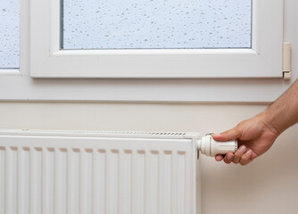 Man's hand adjusting the temperature of a radiator. front view