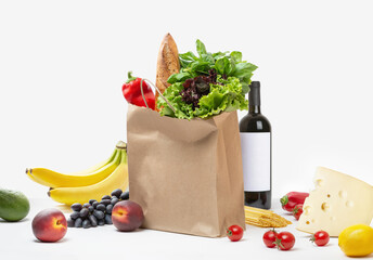 Paper bag with vegetables, fruits, cheese and wine on a white background