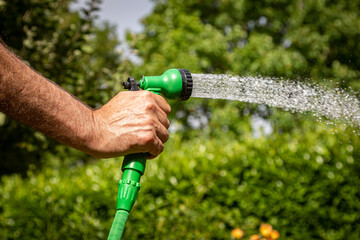 A man watering a garden with a hosepipe, during a dry summer in Sussex