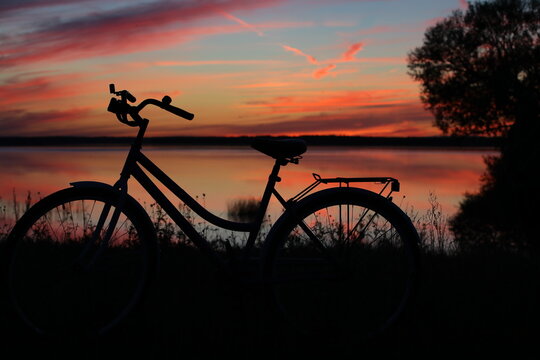 Sunset on the lake with a silhouette of a bicycle on the shore