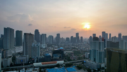 Fototapeta premium Aerial view of office buildings in Jakarta central business district and noise cloud when sunset. Jakarta, Indonesia, August 1, 2022