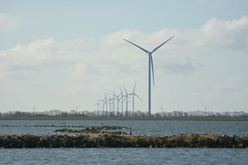 Fototapeta na wymiar Offshore wind turbines at Amstelmeer, Netherlands. Dutch windmill park in the North sea. Space for text. 
