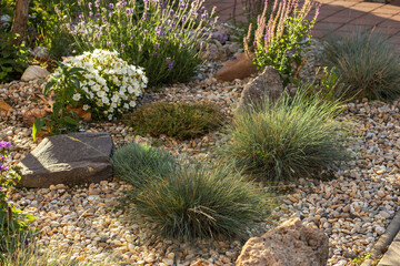 Decorated colorful flowerbed with stones as a decorative elements. Landscape design.