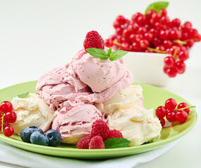 Vanilla and raspberry ice cream scoops on a round green plate