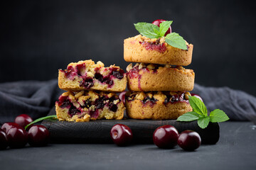 Portion crumble pie with cherries on a wooden board decorated with green mint leaves
