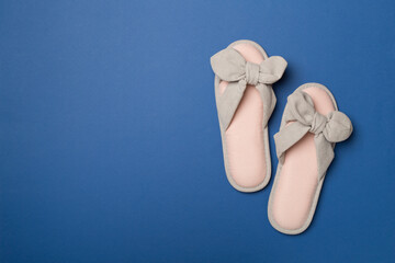 Soft pink slippers on color background, top view