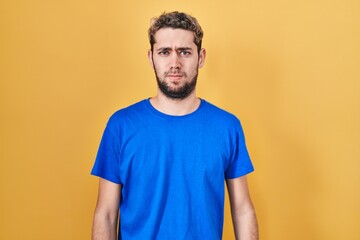Fototapeta premium Hispanic man with beard standing over yellow background skeptic and nervous, frowning upset because of problem. negative person.
