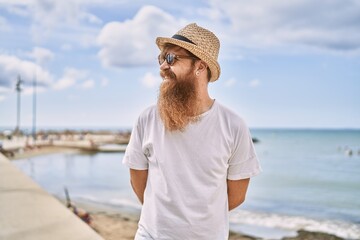 Young redhead tourist man smiling happy standing at the beach.