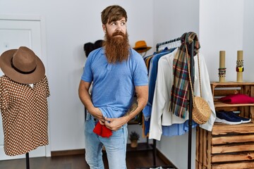 Young redhead robber man stealing shirt at clothes store.