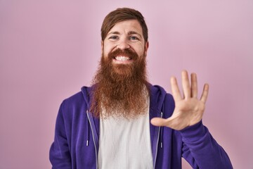 Caucasian man with long beard standing over pink background showing and pointing up with fingers number five while smiling confident and happy.