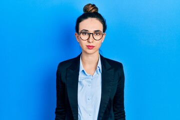 Young hispanic girl wearing business clothes and glasses relaxed with serious expression on face. simple and natural looking at the camera.