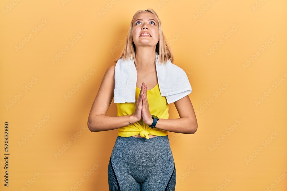 Poster beautiful blonde sports woman wearing workout outfit begging and praying with hands together with ho